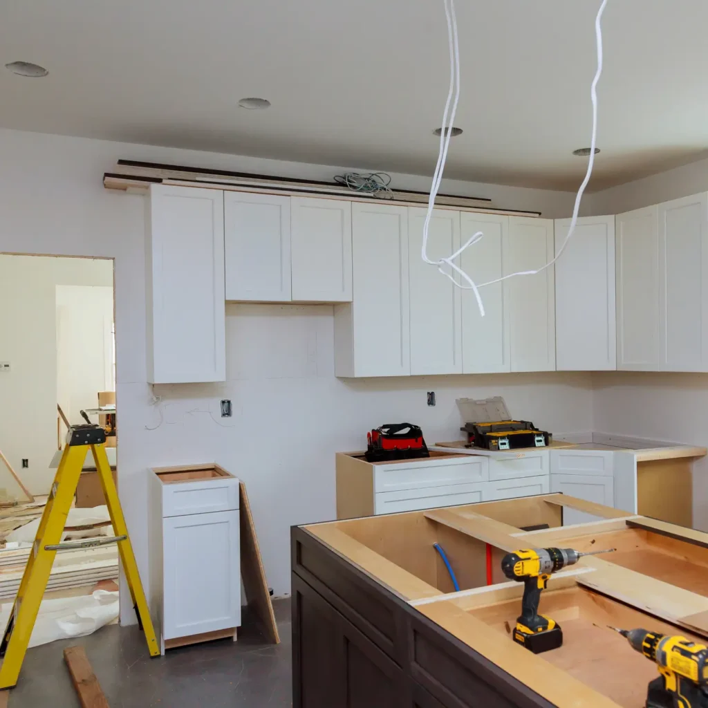 Kundenprojekt Küchenaufbau Hamburg: Weiße Hängeschränke und dunkle Kücheninsel werden mit Werkzeug installiert