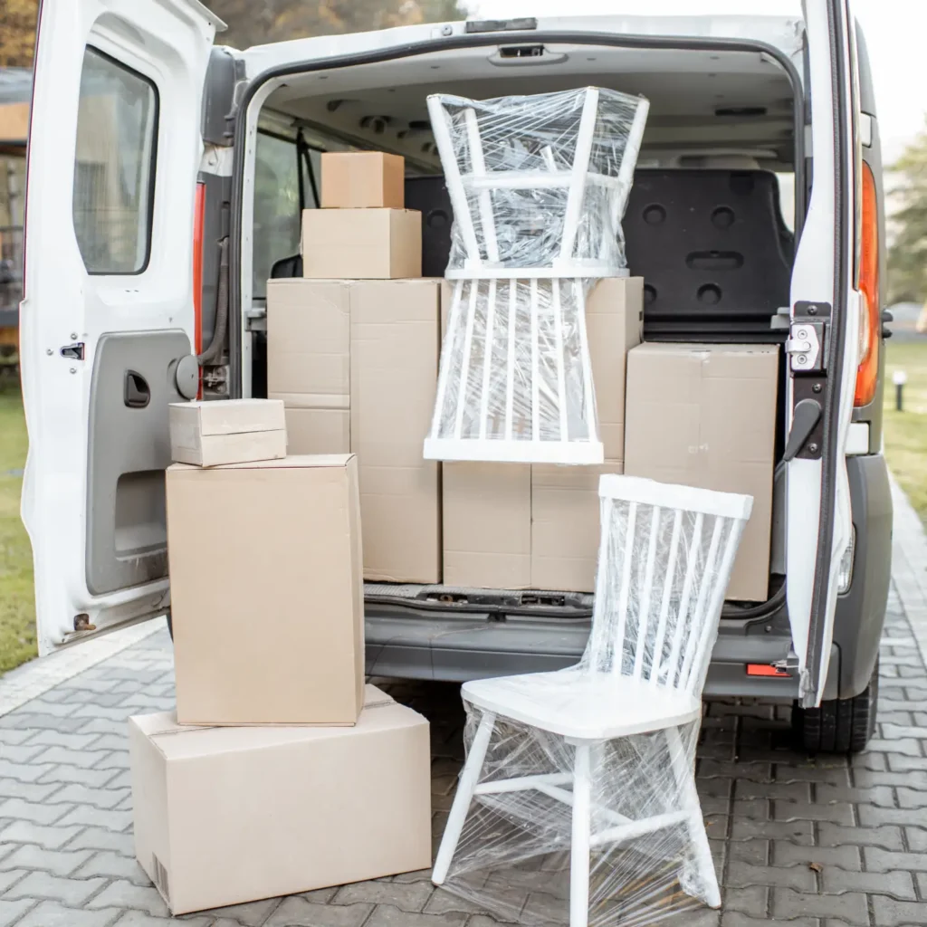 Weißer Transporter, dessen Heckklappe geöffnet ist und verpackte Stühle und Umzugskartons zeigt – Möbeltaxi Hamburg