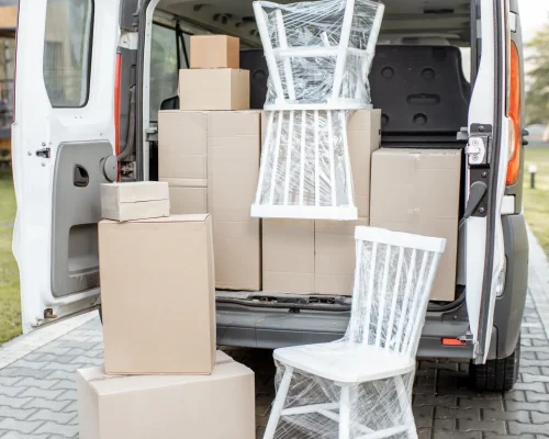 Weißer Transporter, dessen Heckklappe geöffnet ist und verpackte Stühle und Umzugskartons zeigt – Möbeltaxi Hamburg
